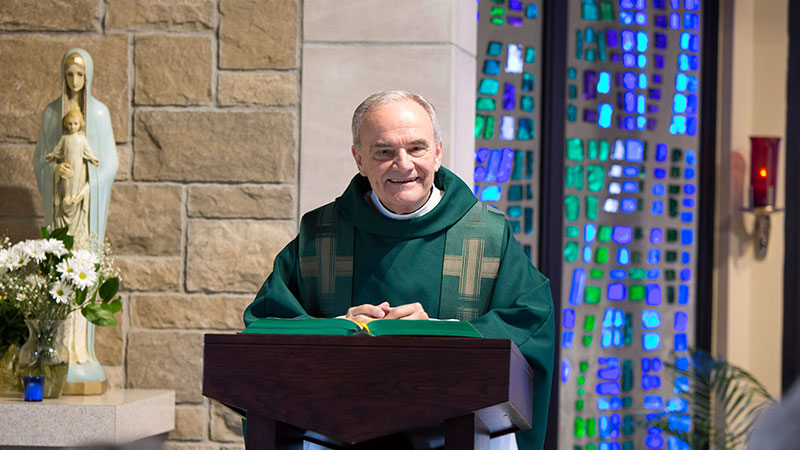 priest smiling as he stands behind his podium